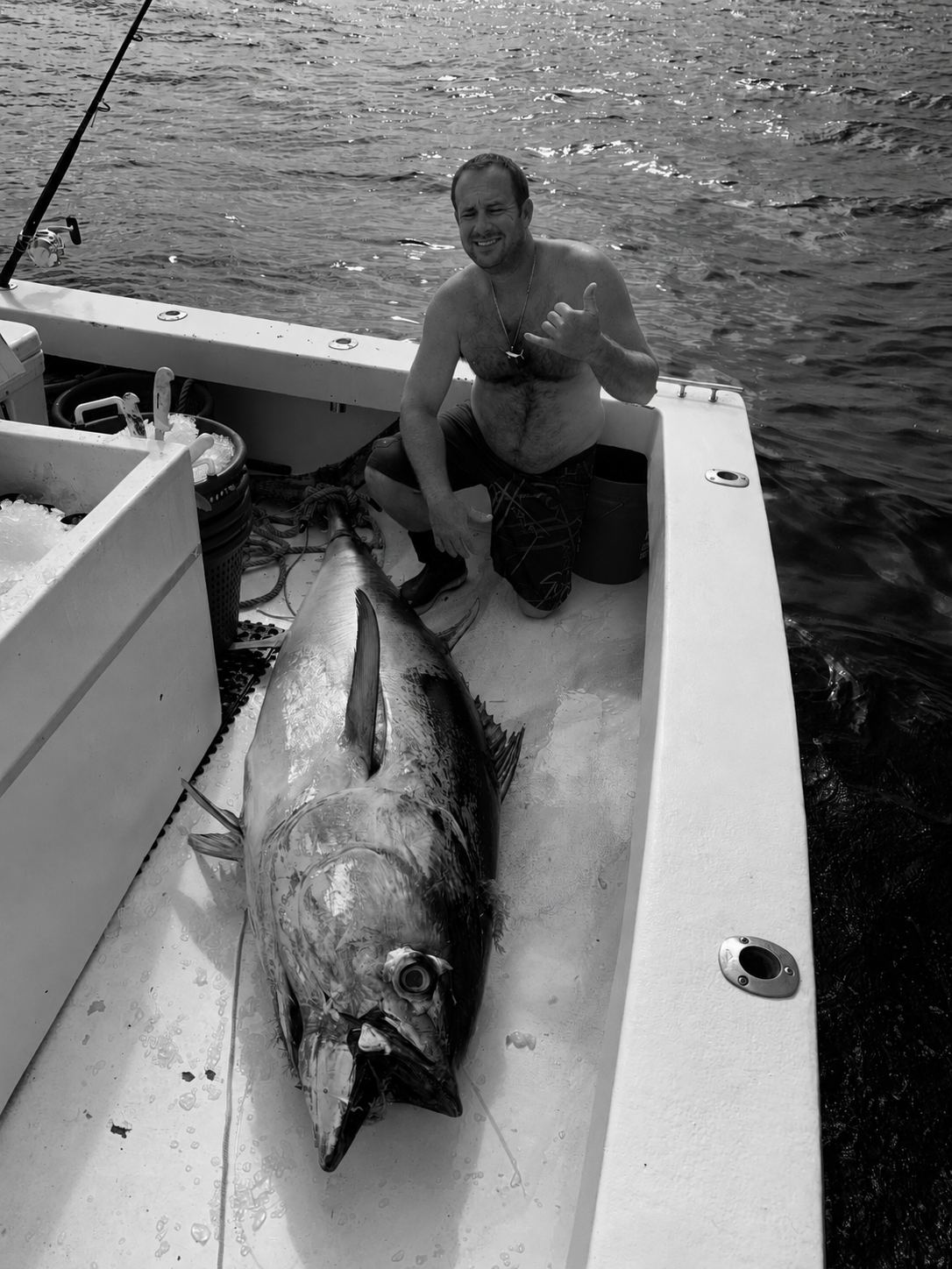 Fisherman aboard an offshore boat in Florida at night with a large swordfish stretched across the deck.