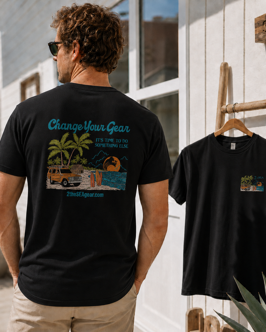 Back lifestyle view of The Departure Black 2theSEA T-shirt featuring the large Change Your Gear beach graphic in a coastal setting.
