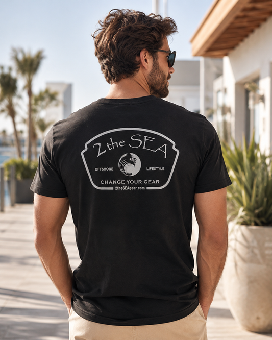 Back lifestyle view of The Mark dark grey 2theSEA T-shirt featuring the large light Change Your Gear badge graphic in a coastal setting.