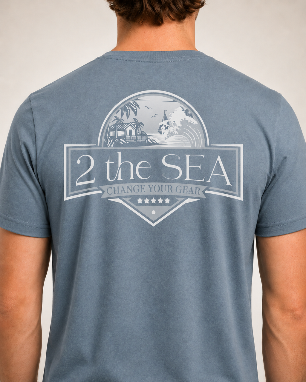 Close-up back view of the Shore House Slate Blue 2theSEA T-shirt showing the large coastal house, palm and wave graphic.