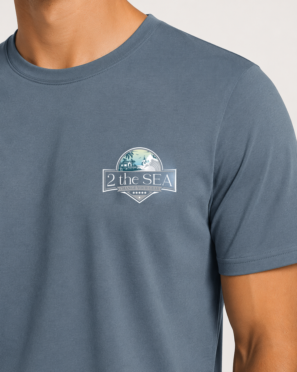 Close-up front view of the Shore House Slate Blue 2theSEA T-shirt showing the coastal house, palm and wave graphic on the left chest.