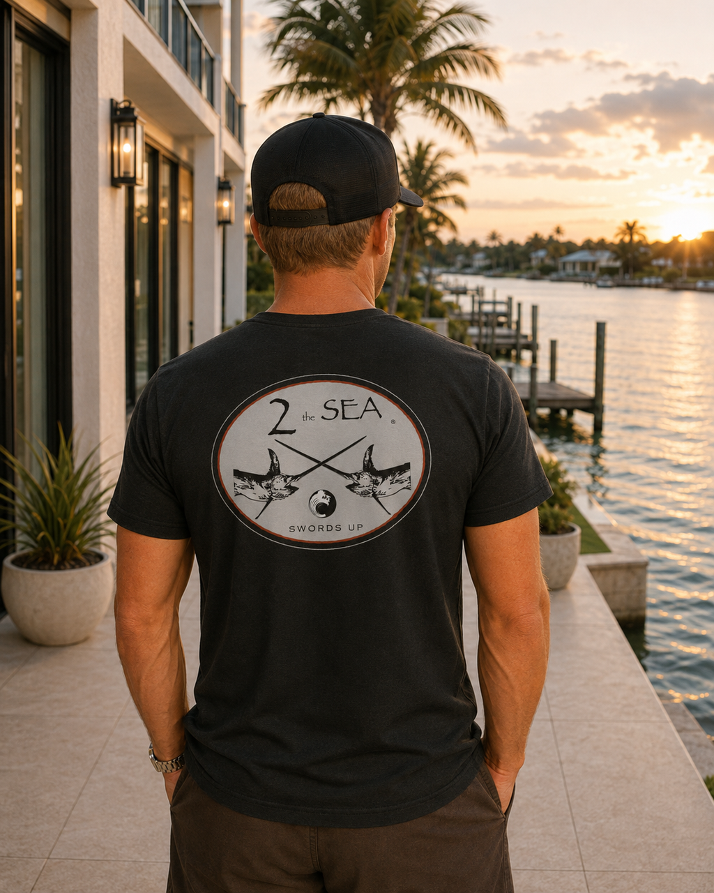 Back lifestyle view of The Crossing Black 2theSEA T-shirt featuring the crossed-swordfish graphic in a refined waterfront setting.