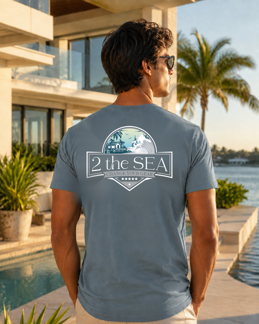 Front view of the Shore House Slate Blue 2theSEA T-shirt featuring the small coastal chest graphic in a waterfront lifestyle setting.